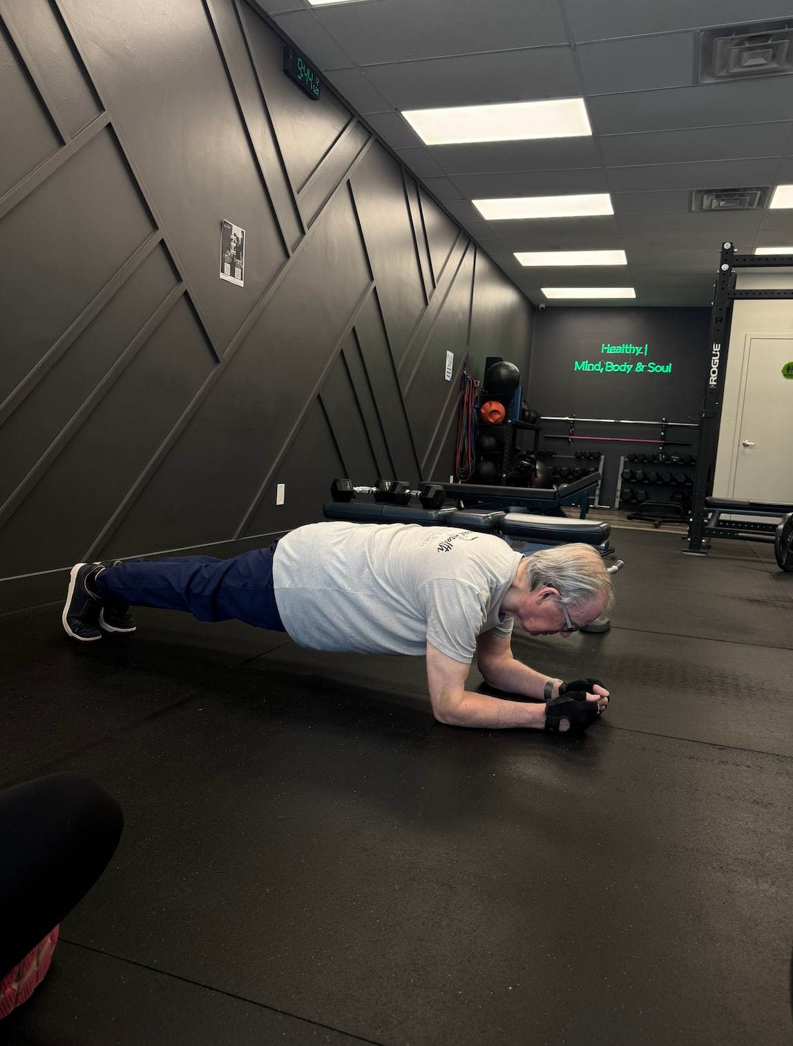 Henk, the studio's star member over 70, holding a forearm plank on the training floor at Balanced Health Fitness in Seaford, NY.